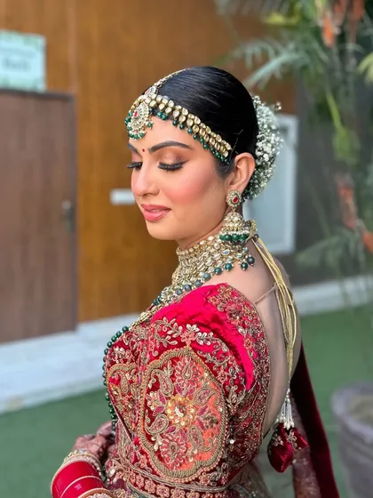 A side profile of this scarlet and metallic gold bridal look, showcasing the intricate hair and the flawless, glowing skin.