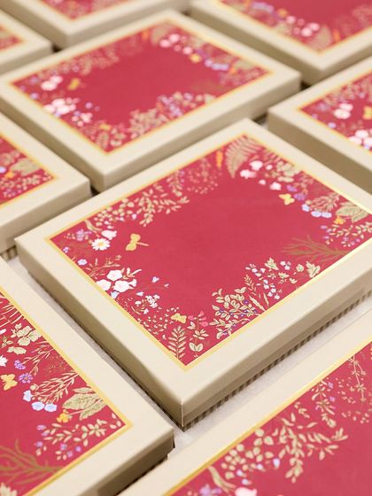 An array of our custom-designed corporate gift boxes, showcasing the elegant red and gold floral motif.