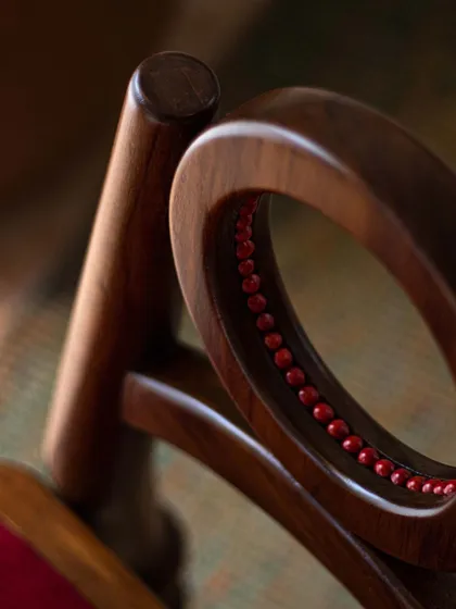 A close-up of the Manjadi chair's backrest, where real Manjadikuru seeds are embedded within the circular frame. This detail offers a tactile experience, inviting you to connect with the story and cultural significance of the piece.