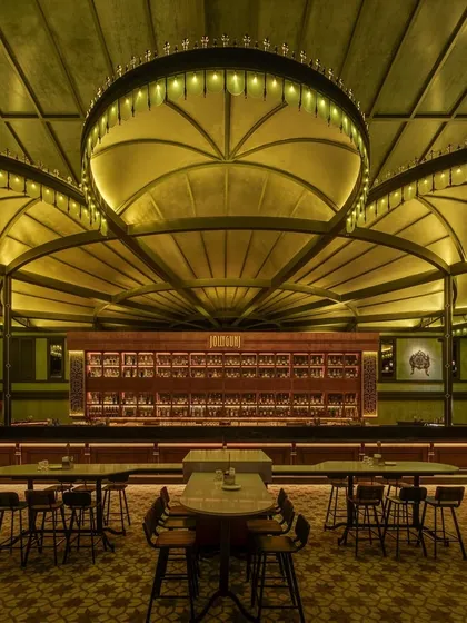The main bar area at night, with the custom lighting creating a warm, inviting atmosphere. The patterned floor tiles and dark wood finishes contribute to the classic, sophisticated vibe of this restaurant interior.