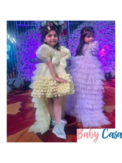 Twinning in style for a party. These sisters are wearing our high-low ruffled dresses in lemon yellow and lavender, perfect for dancing and making a fashion statement at any celebration.