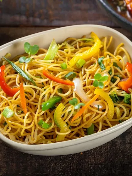 Vegetable chow mein with colorful bell peppers. The shot is tightly framed to emphasize the texture of the noodles and vegetables.