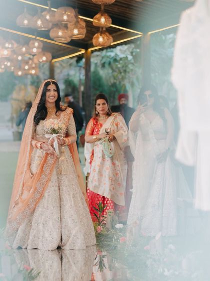 A beautiful shot of the bride during her entrance, captured through a reflection, adding a dreamy and artistic quality to the moment.