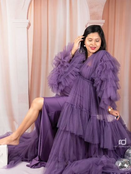 A glamorous solo portrait. The mom-to-be looks stunning in a purple gown, surrounded by disco balls for a touch of sparkle and fun.