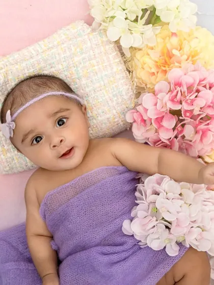 The combination of the soft purple wrap and the surrounding pastel flowers beautifully complements this baby's alert expression. This shot shows how I incorporate color to enhance the mood of the portrait.