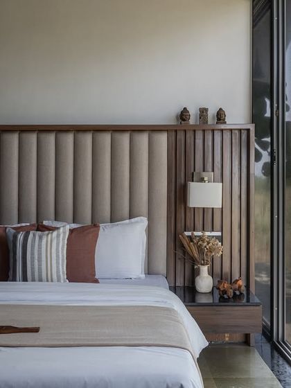 For the Midas Resort, we designed this bedroom to be a serene escape. The room features a custom headboard with vertical upholstery and wood paneling, creating a textural backdrop. A large sliding glass door opens directly to a private garden, blurring the line between indoors and out.