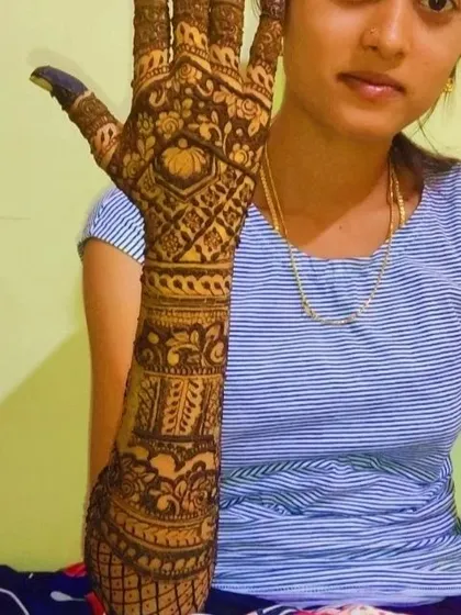 A close-up of a single hand, showing a detailed design with a central geometric pattern, surrounded by traditional motifs.