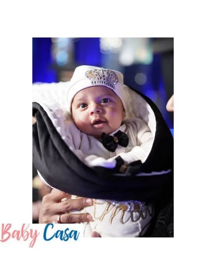 This little gentleman is ready for his first big event. He looks so sharp in his black bow tie and crown detailed cap, snuggled warmly in a personalized black and white wrap.