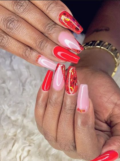 A vibrant set of long coffin nails with a mix of solid red, a nude base, and red glitter foil accents.