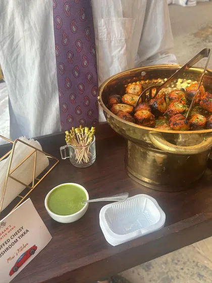 Stuffed Cheesy Mushroom Tikka served with mint chutney. A server presents the tray, showcasing my attentive service style.