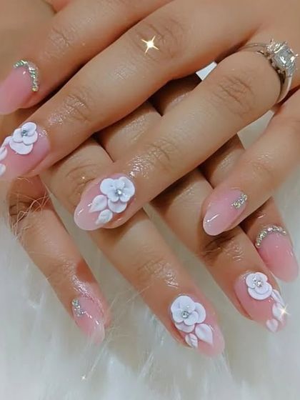 This elegant almond-shaped nail set features a sheer pink base, 3D white flowers, and a crescent of rhinestones at the cuticle for a touch of glam.