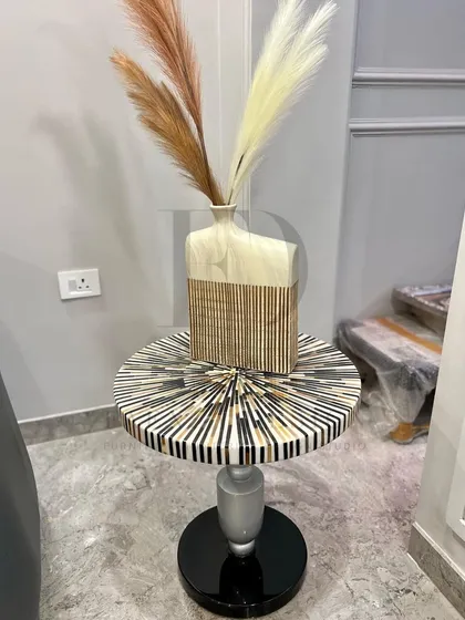 A side table featuring a striking sunburst-patterned inlay top. The combination of black, white, and gold tones on a classic pedestal base creates a piece that is both artistic and functional.