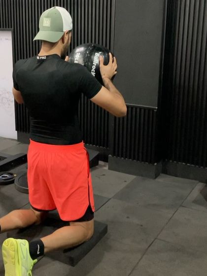 A kneeling rotational medicine ball throw, isolating the upper body and core to maximize rotational power development.