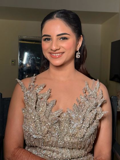 A smiling portrait of the bride in her stunning silver gown. The makeup is elegant and sophisticated, perfect for a formal evening event.