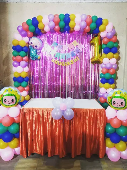 A Cocomelon theme for a first birthday party. This decoration uses a multi-colored balloon arch and character pillars, perfect for the youngest party-goers.