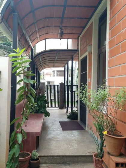 A long, covered walkway lined with plants, leading to the entrance of the home.