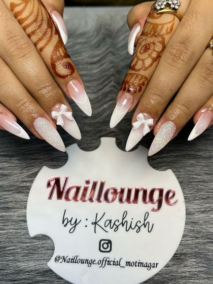 A classic bridal look with a modern feel. These stiletto nails feature a beautiful white ombre effect, with glitter accent nails and delicate white 3D bows for a touch of elegance.