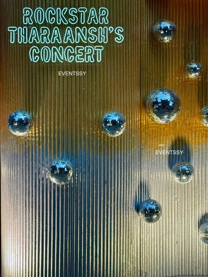 A detail shot of the rockstar party decor, with a custom neon sign and mini disco balls on a textured gold wall. These elements add sparkle and reinforce the glamorous concert vibe.