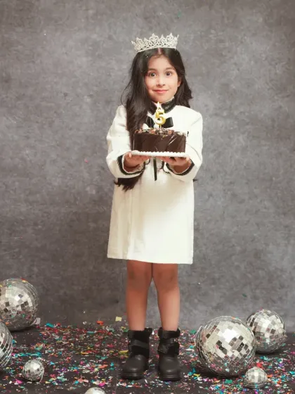 A stylish 5th birthday portrait. This young lady is celebrating with a chocolate cake, confetti, and disco balls for a fun party-themed shoot.