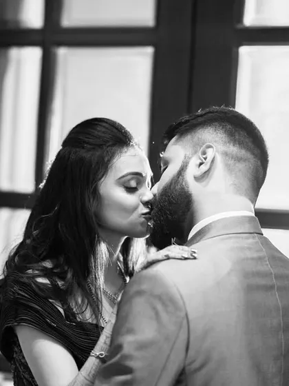 A timeless black and white photograph that captures a quiet, intimate kiss against a beautifully lit window. This style of photography adds a layer of drama and romance, focusing on emotion and connection without the distraction of color.