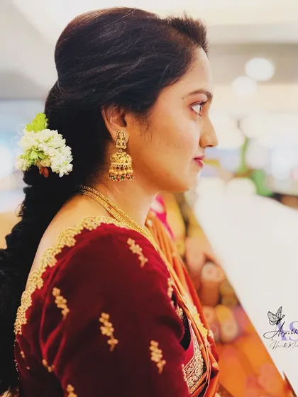 A side profile showcasing a traditional braided hairstyle adorned with fresh jasmine flowers. This classic look is perfect for a muhurtham ceremony, combining fragrance and beauty.