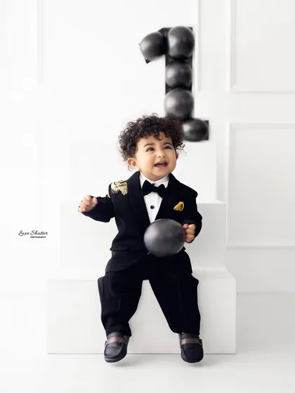 Celebrating a first birthday in style. This little gentleman is all smiles in his sharp tuxedo, showing that milestone sessions can be both fun and incredibly dapper.