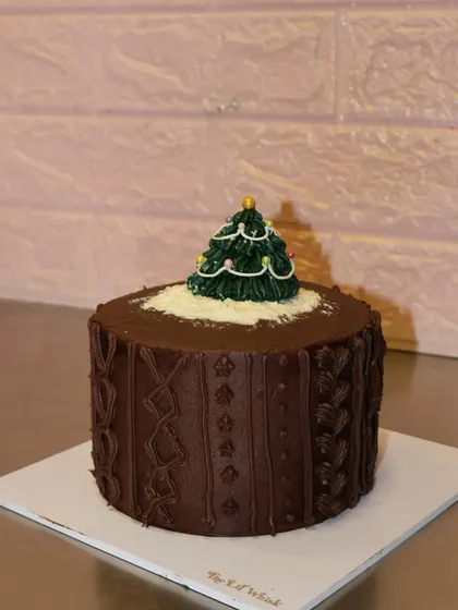 Our cozy Christmas sweater cake. This chocolate cake is decorated with a cable-knit pattern and topped with a tiny buttercream Christmas tree.