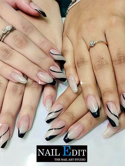 This design showcases two different but complementary styles. One hand features a modern French with black tips and swirling lines, while the other has a sparkling glitter base, demonstrating our ability to create coordinated mismatched sets.