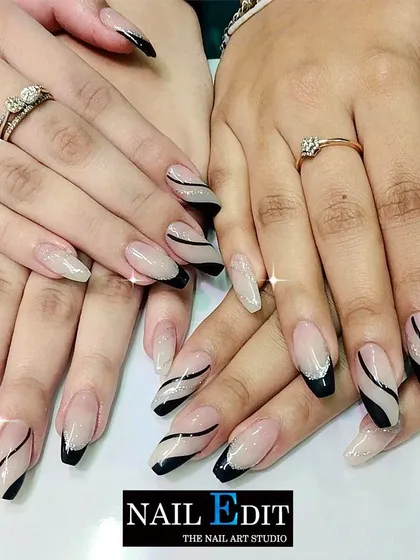 This design showcases two different but complementary styles. One hand features a modern French with black tips and swirling lines, while the other has a sparkling glitter base, demonstrating our ability to create coordinated mismatched sets.