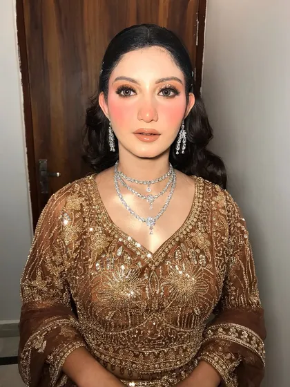 The frontal view shows how the necklace complements her shimmery outfit and glam makeup.