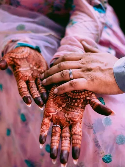 A beautiful, symbolic photo of the bride and groom's hands. The bride's deep henna stain is a sign of the love and blessings surrounding them.