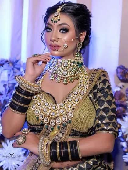 A confident portrait of the bride, showcasing her heavy kundan jewelry against the dark, patterned blouse.