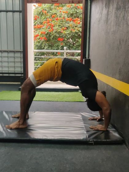 Holding a strong bridge pose on the mat, this adult student demonstrates his improving flexibility.