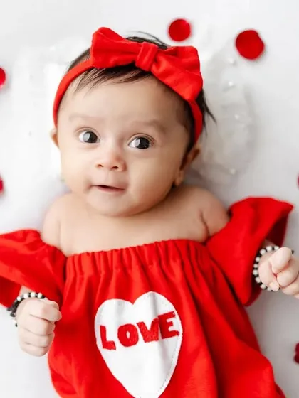 A sweet, wide-eyed baby ready to celebrate her first Valentine's Day.