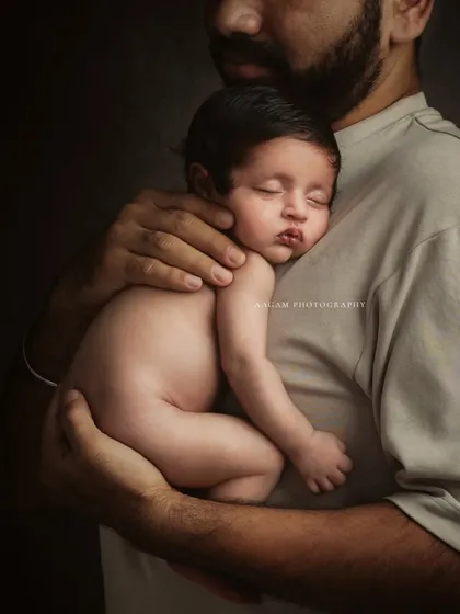 A father's embrace. This close-up shot focuses on the peaceful sleep of the newborn, safe and secure against his dad's chest.