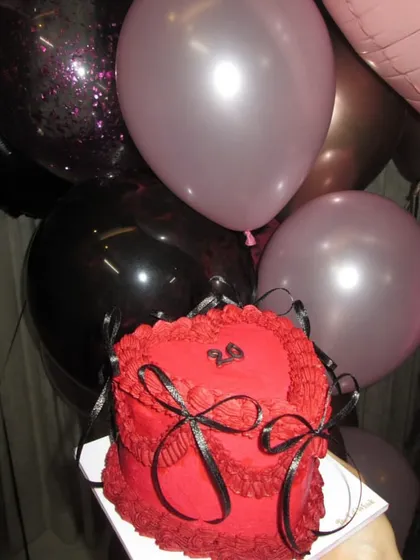 Our red and black vintage heart cake, pictured with party balloons, ready to be the centerpiece of a stylish birthday party.