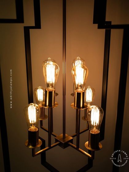 Inspired by Art Deco design, this hanging fixture features a strong geometric black frame with exposed vintage-style filament bulbs. The combination of black and warm gold tones provides a sophisticated, retro feel for dining areas or entryways.