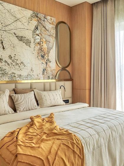 A master bedroom that exudes luxury. The headboard wall features a stunning slab of marble from The Quarry Gallery, framed by honey oak veneer panels and a touch of brass for a high-end finish.