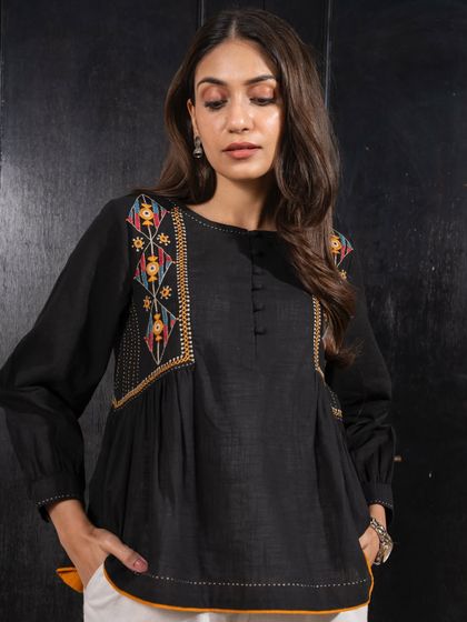 This Paheli black top features stunning Pakka embroidery on the shoulders and yoke. It’s a versatile piece that can be paired with pants or a skirt for a chic, handcrafted look.