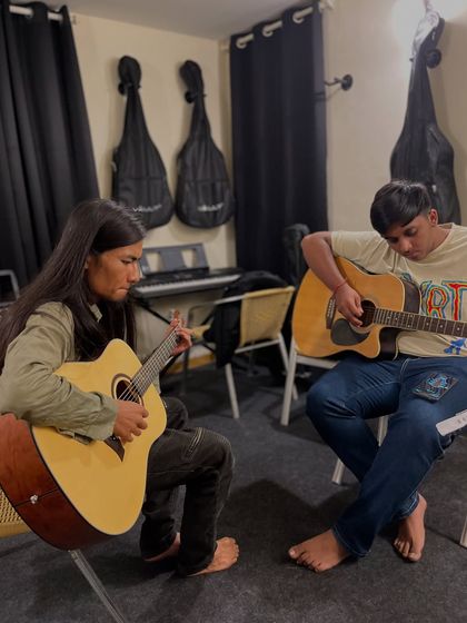 A teacher and student working together during a guitar lesson. This one on one attention ensures that each student gets personalized feedback to help them improve.