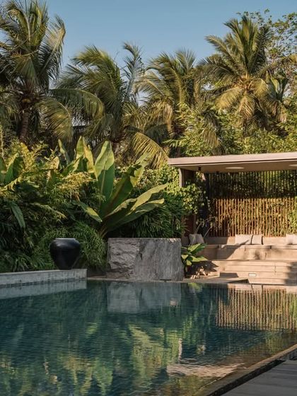 The poolside at GAIA, where we used large, dark urns as sculptural elements against the backdrop of a tropical garden. The design creates a serene, resort-like atmosphere.