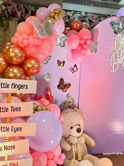 A closer view of the custom signage and teddy bear, surrounded by pink and rose gold balloons with butterfly accents.
