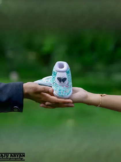 It's the little details that tell the big story. This close-up shot of the parents-to-be holding a tiny pair of baby shoes is a simple yet powerful way to symbolize the new life they are waiting to welcome.