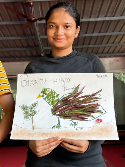 A camper proudly displays her artwork of a Bronze-winged Jacana, created using natural materials found around the Ulavi campsite.