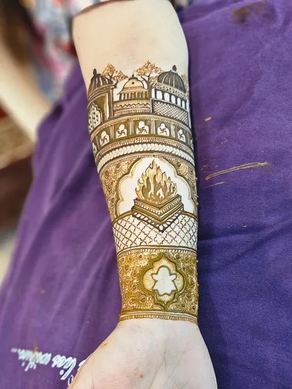 The arm portion of a highly personalized bridal design. This features the family's home temple and the sacred wedding fire, telling a story that is unique to the client.
