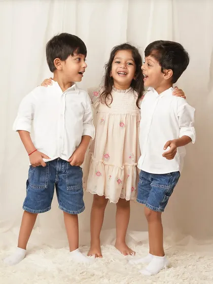 A candid shot of the three siblings interacting and laughing together. This shows the fun and energy that older kids bring to a family photoshoot.