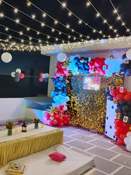 A modern and stylish terrace setup for a Diwali card party. This decor features a glittering gold sequin backdrop, a 'Let's Party' neon sign, and themed balloon arches, all illuminated by strings of fairy lights for a festive casino night vibe.