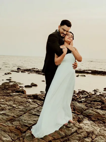 A romantic embrace on a rocky shore, with the bride in a beautiful white dress. This elegant yet candid shot combines classic style with a natural, windswept setting.
