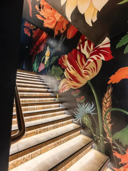 The illuminated steps of this staircase highlight the detailed tile work and the rich colors of the surrounding floral mural. The combination of art and architectural lighting creates a truly captivating ascent.