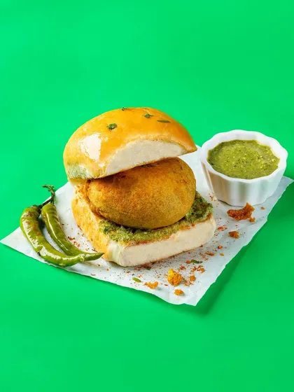 A deconstructed Vada Pav with green chutney and chillies. This clean, studio-lit shot for Bistro by Blinkit is designed for online food delivery menus.